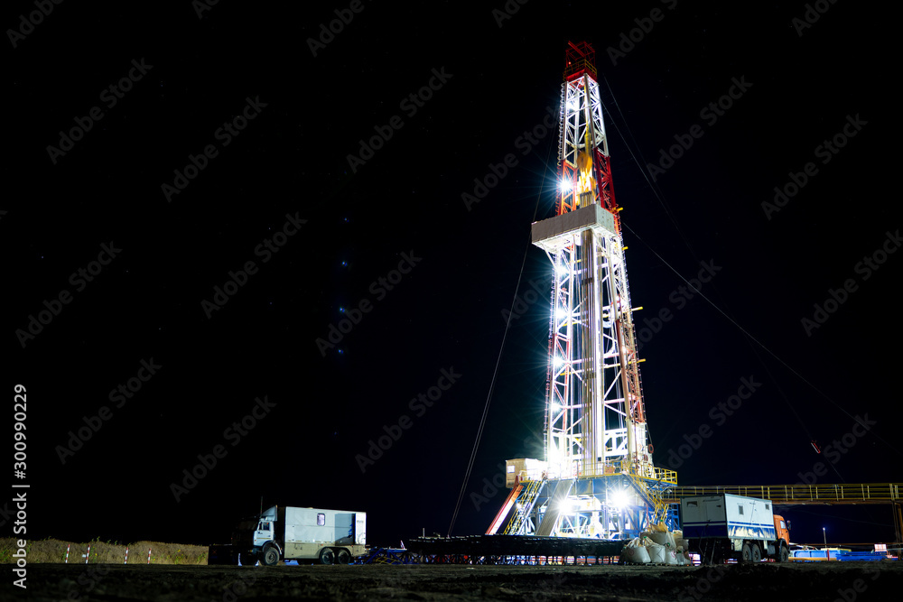 Oil and Gas Drilling Rig. Oil drilling rig operation on the oil platform in oil and gas industry. Beautiful night view of derrick drilling rig in offshore gas field.