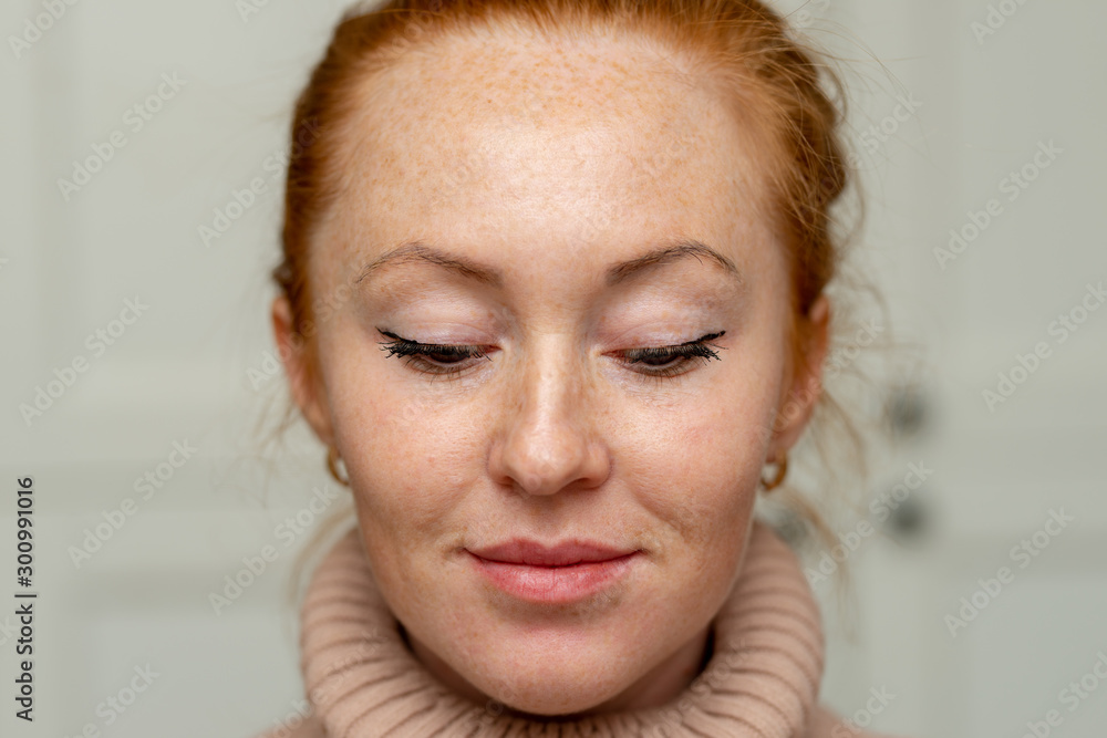 Portrait of beautiful pensive girl with red hair at home. Cute redhead and freckles woman face closeup portrait with healthy skin Portrait of beautiful pensive girl with red hair at home. Cute redhead and freckles woman face closeup portrait with healthy skin