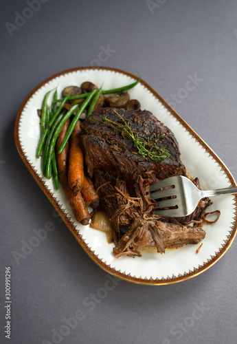 Slow cooked beef roast with carrots and green beans with thyme garnish. 