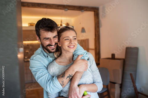 Young couple moving into new home.They standing in living room and embracing each other.