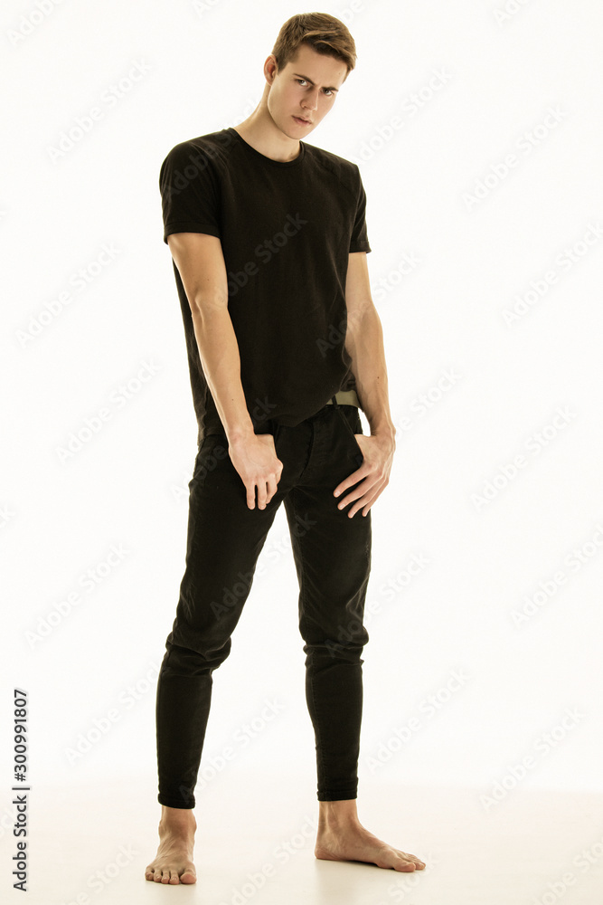 Muscle strong beautiful stripped male model in denim jeans and black t-shirt with belt on white isolated font background Muscle strong beautiful stripped male model in denim jeans and black t-shirt with belt on white isolated font background