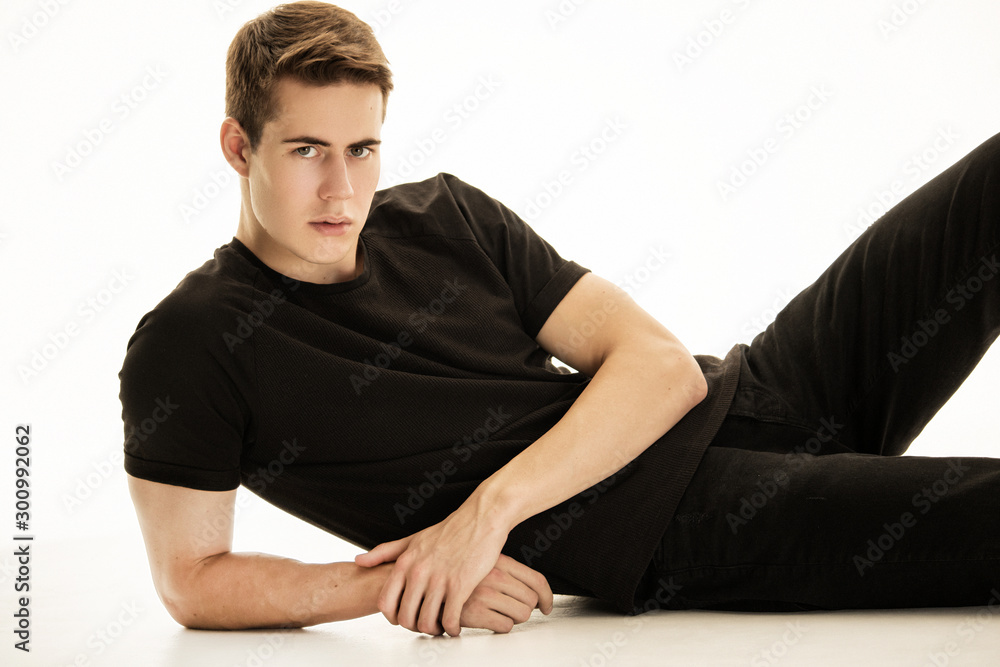 Muscle strong beautiful stripped male model in denim jeans and black t-shirt with belt on white isolated font background Muscle strong beautiful stripped male model in denim jeans and black t-shirt with belt on white isolated font background