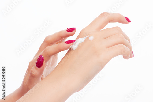 elegant female hands with red pink nails applying cream