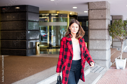 pretty young woman walking leaving an Hotel wearing autumn elegant clothes
