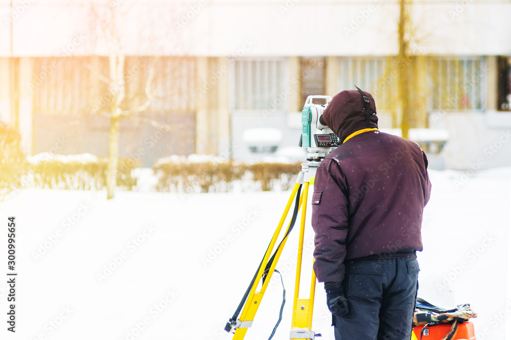 Surveyor engineer uses a total station at a construction site. Geodetic works. Building construction Surveyor engineer uses a total station at a construction site. Geodetic works. Building construction
