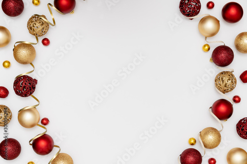 New Year and Christmas frame. Red and golden Christmas decorations - shiny balls and decorative ribbon on white paper background. Top view, flat lay, copy space