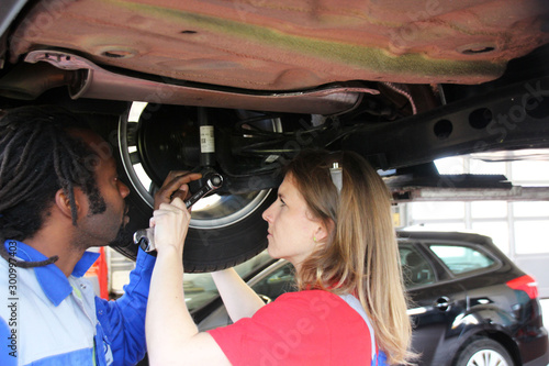 Man and woman working together repairing a car in the Automobile garage