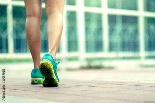 Runner feet running on concrete road in park - fitness sunrise jog workout welness concept
