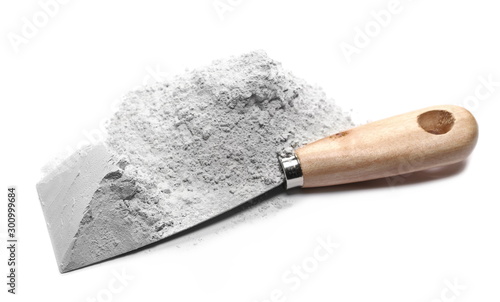 Pile of cement powder and metal industrial working spatula tool isolated on white