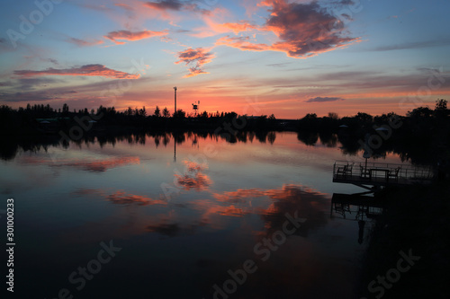 sunset on a lake with pink clouds. water like mirror