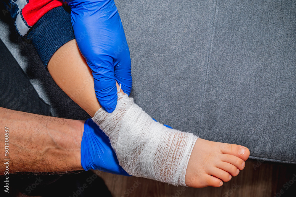 Bandaging of the child's foot. Health and pharmaceutical concept, child