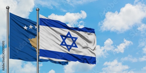 Kosovo and Israel flag waving in the wind against white cloudy blue sky together. Diplomacy concept, international relations.