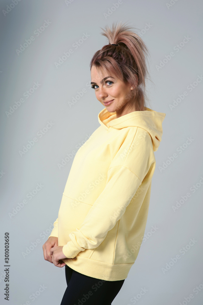 Close up of young attractive caucasian woman in yellow hoodies looking at camera posing funny, shocked with expression. Positive emotions of girl. Model tests on white background Close up of young attractive caucasian woman in yellow hoodies looking at camera posing funny, shocked with expression. Positive emotions of girl. Model tests on white background
