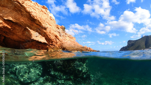 Above and below photo of tropical exotic island arch cave with open ocean emerald sea and deep blue cloudy sky