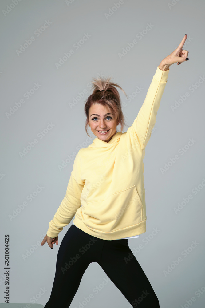 Close up of young attractive caucasian woman in yellow hoodies looking at camera posing funny, shocked with expression. Positive emotions of girl. Model tests on white background Close up of young attractive caucasian woman in yellow hoodies looking at camera posing funny, shocked with expression. Positive emotions of girl. Model tests on white background