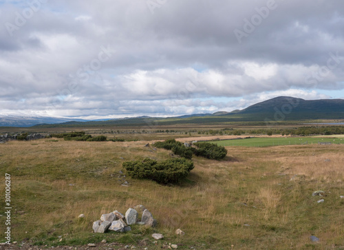 Autumn view on hills and snow capped mountains with dramatic clouds at Dovre Nasjonaalpark nature park from main road E6  Norway