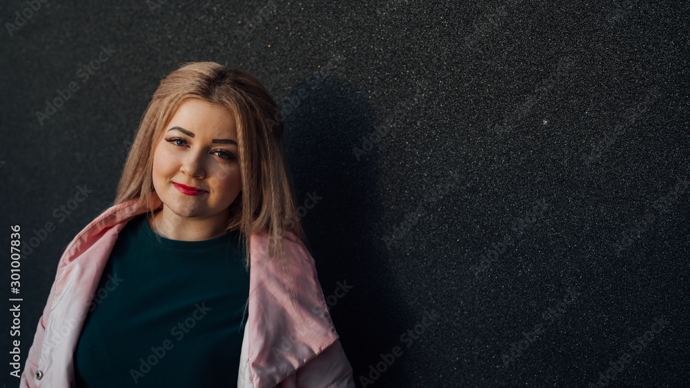 A portrait of a beautiful girl, posing against the background of a gray wall. A portrait of a beautiful girl, posing against the background of a gray wall.