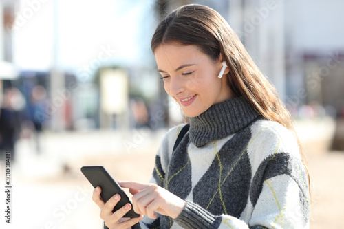 Happy girl listens to music using mobile phone in winter