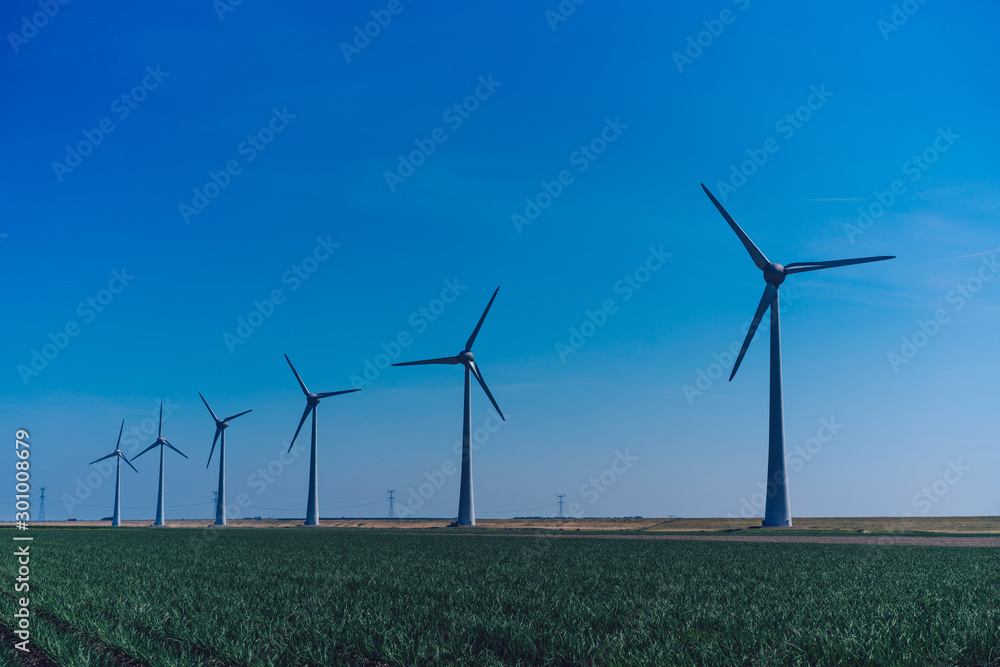 Metallic huge windmill in rural field area covered with wind blowing proving clean ecological alternative power from nature. Alternative electricity generation Metallic huge windmill in rural field area covered with wind blowing proving clean ecological alternative power from nature. Alternative electricity generation