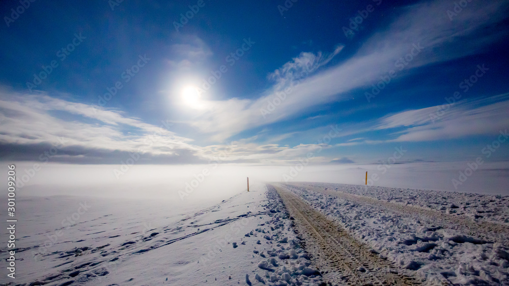 Route en islande à travers la neige qui s'enfonce dans les nuages à la lueur de la lune 