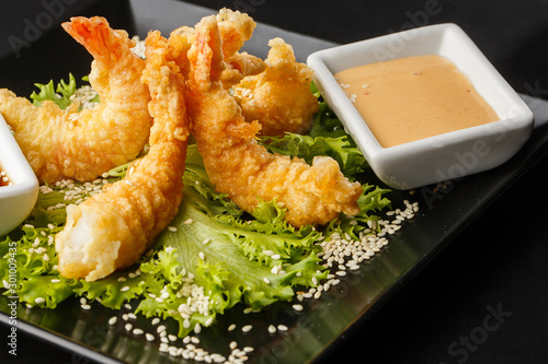 Obraz na płótnie Tempura Deep Fried Shrimp Ebi with sweet chili and soy sauce on black board stone on dark background. Japanese food style appetizer. Deep fried prawn in breeding close up. Horizontal photo. w salonie