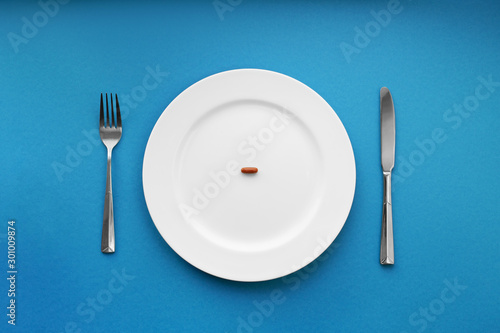 A small tablet in a plate. Medical concept. Eat pills instead of food.