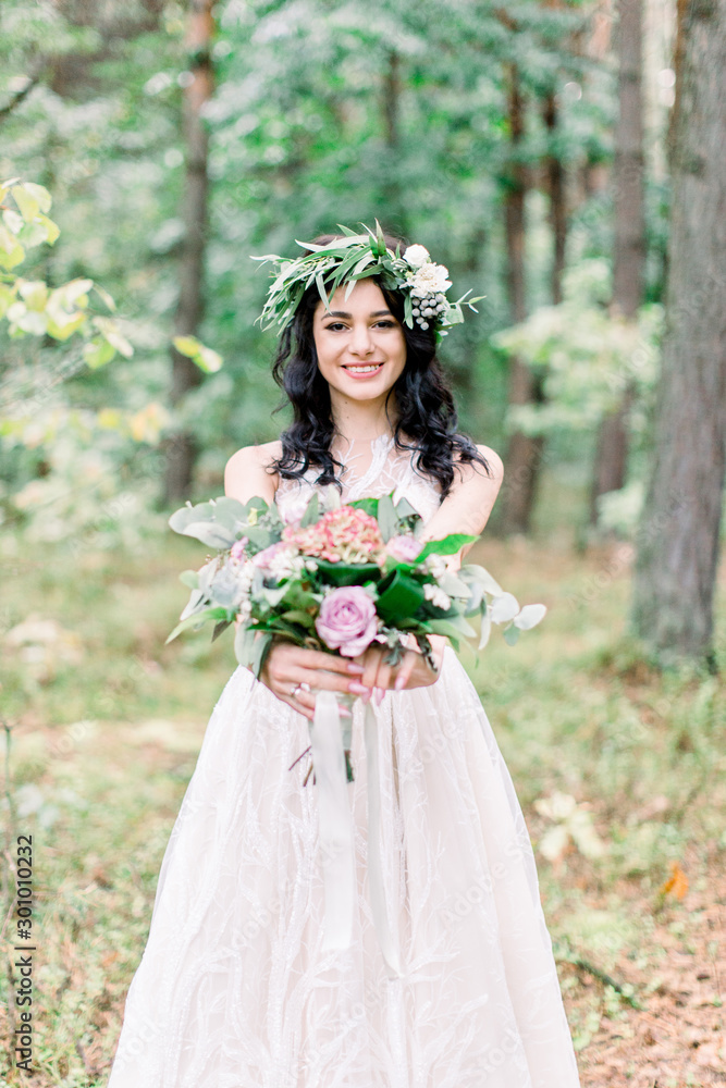 Portrait of a young beautiful bride with eucalypthus wreath on the head, with a rustic bouquet in the forest at wedding walk. Portrait of a young beautiful bride with eucalypthus wreath on the head, with a rustic bouquet in the forest at wedding walk.