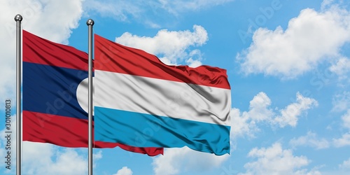 Laos and Luxembourg flag waving in the wind against white cloudy blue sky together. Diplomacy concept, international relations.