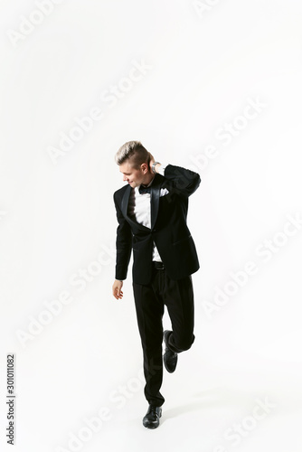 Portrait of young smiling handsome man in tuxedo stylish black suit, studio shot isolated on white background. Showman or toastmaster in jacket with bowtie