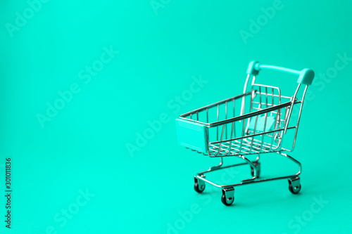 empty metal shopping trolley on green background. Discount and shopping concept