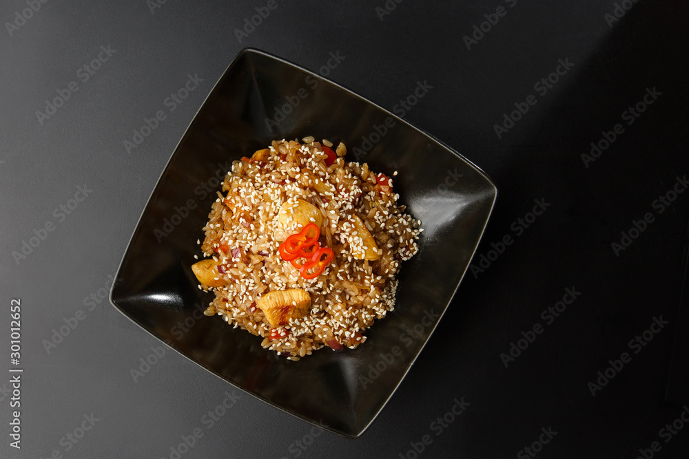 Asian fried rice with eggs, pineapple and sesame close-up on a plate, horizontal view from above. Nigerian food party: Jollof rice with fried chicken close-up on a plate.