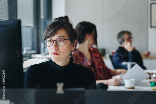 Canvas Print Portrait of  confident businesswoman working on computer in creative office