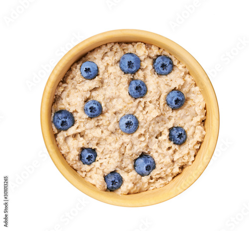 Oatmeal porridge  with blueberry  in wooden bowl isolated on white background. Top view