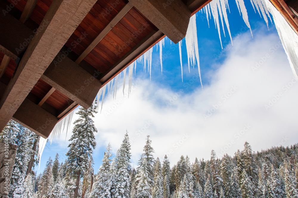 Snow and icicles cover a wooden lodge in Sequoia & Kings Canyon National Park within the Sierra National Forest in California, USA. 
