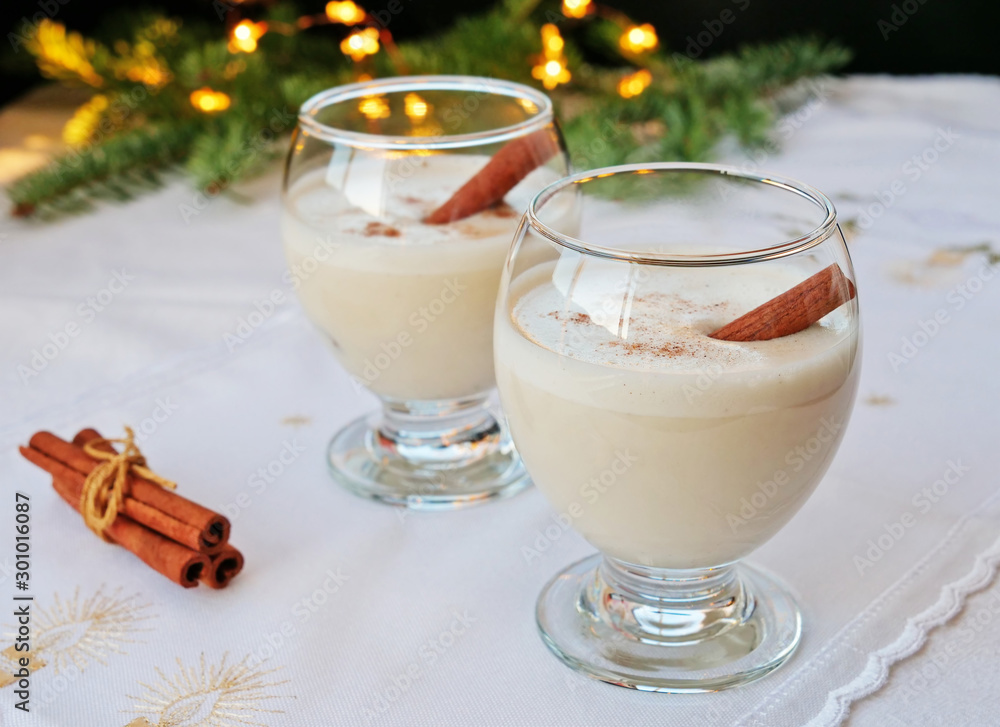 Eggnog in glasses with cinnamon stick on Christmas table Eggnog in glasses with cinnamon stick on Christmas table