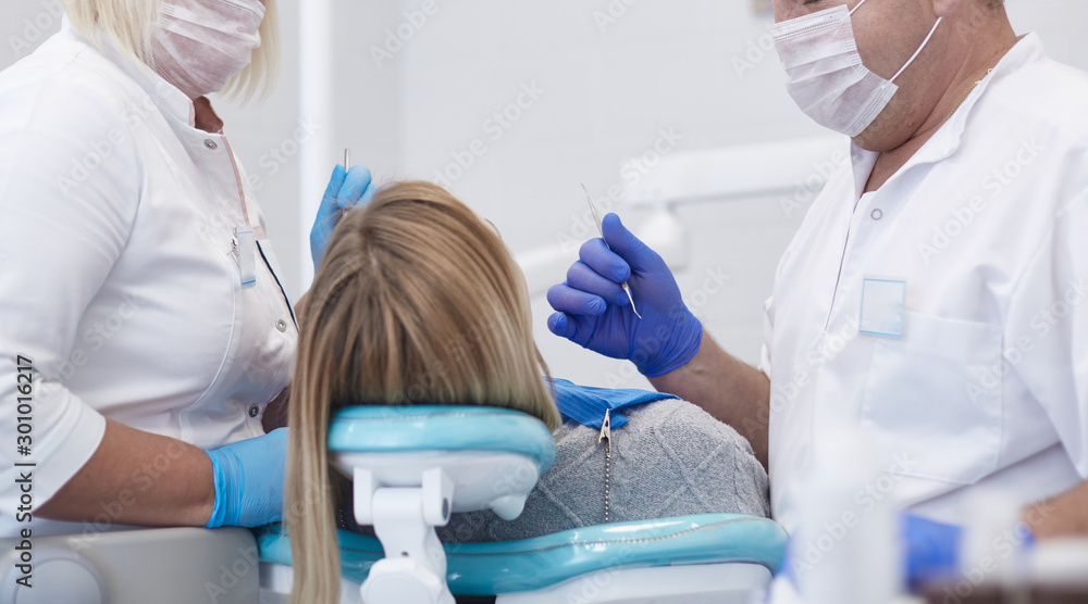 Doctor dentist treats teeth of a beautiful young girl patient. The girl on reception at the dentist. Doctor dentist treats tooth Doctor dentist treats teeth of a beautiful young girl patient. The girl on reception at the dentist. Doctor dentist treats tooth