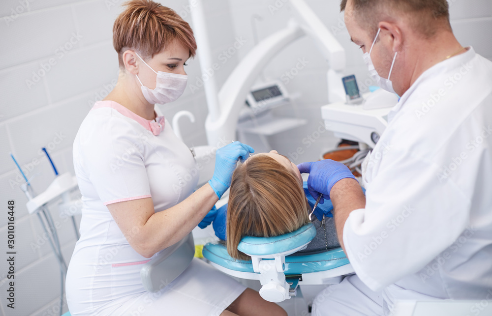 Doctor dentist treats teeth of a beautiful young girl patient. The girl on reception at the dentist. Doctor dentist treats tooth Doctor dentist treats teeth of a beautiful young girl patient. The girl on reception at the dentist. Doctor dentist treats tooth