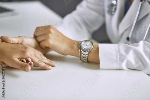 Woman doctor calms patient and holds hand