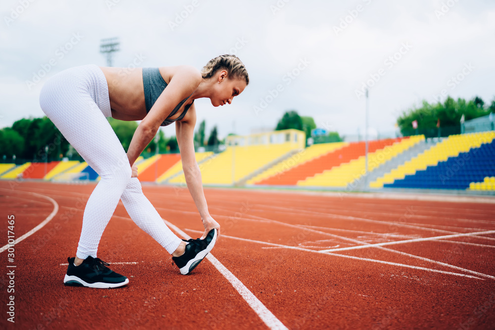 Runner doing physical exercises in stadium Runner doing physical exercises in stadium