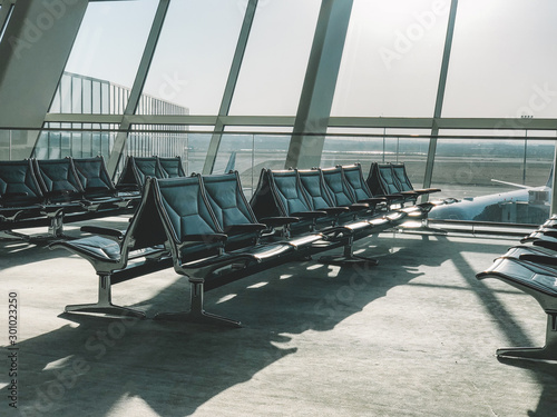 Light waiting area of airport with big windows.Interior of modern waiting room of airport with huge glass windows and rows of seats in sunlight © BullRun