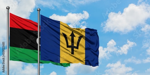 Libya and Barbados flag waving in the wind against white cloudy blue sky together. Diplomacy concept, international relations.