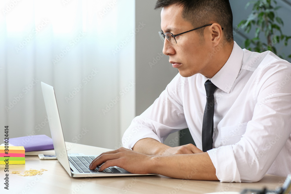 Asian businessman working on laptop in office Asian businessman working on laptop in office