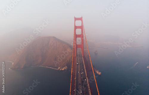 Aerial view of Golden Gate Bridge in foggy visibility during evening time, metropolitan transportation  infrastructure, birds eye view of automotive car vehicles on road of suspension construction
