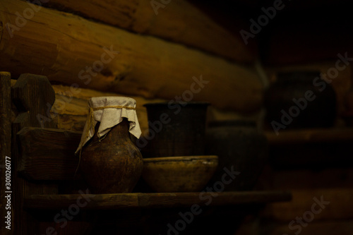 An old jug of milk with sour cream is covered with a rag on a shelf in a closet. Old clay jug at the grandmother s house.