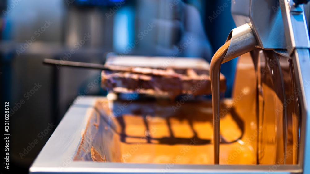 Chocolate flowing from machine in chocolate factory Chocolate flowing from machine in chocolate factory