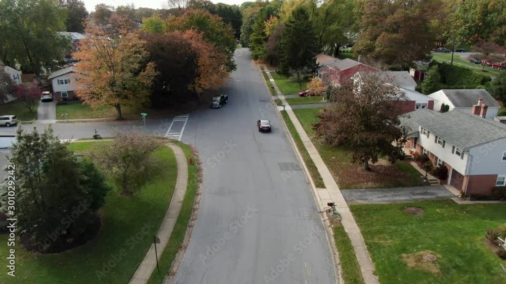 AERIAL Cars Drive Down A Road In A Small Housing Estate In The Fall