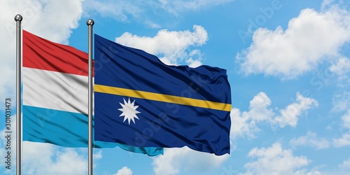 Luxembourg and Nauru flag waving in the wind against white cloudy blue sky together. Diplomacy concept, international relations.