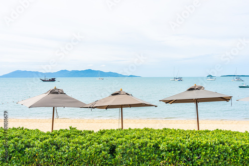 Beautiful tropical beach sea and ocean with coconut palm tree and umbrella and chair on blue sky and white cloud