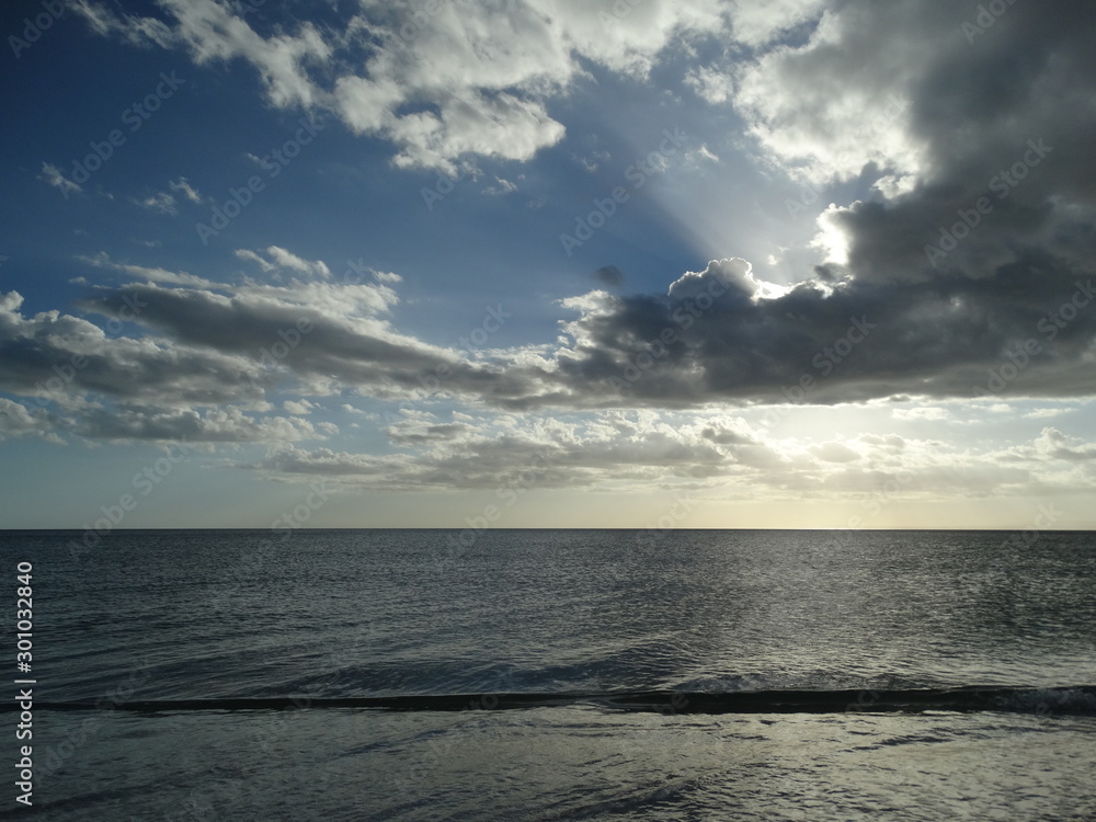 Obraz premium dramatic sun and clouds overcalm ocean water in florida