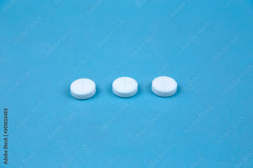 Three white round pills on blue background. Concept of healthcare and medicine communication. Three white round pills on blue background. Concept of healthcare and medicine communication.